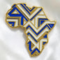Broche Renaissance Ébène Likolo en forme de carte d'Afrique, émail bleu et blanc avec détails dorés géométriques.