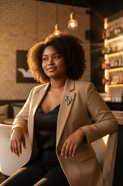 Femme portant la broche Renaissance Ébène Harlem 1925 au design géométrique Art déco sur un blazer beige élégant